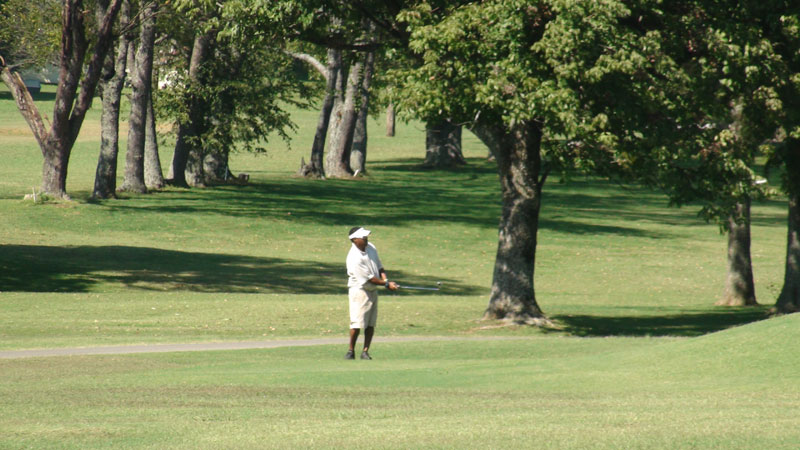 Man in white outfit playing golf.