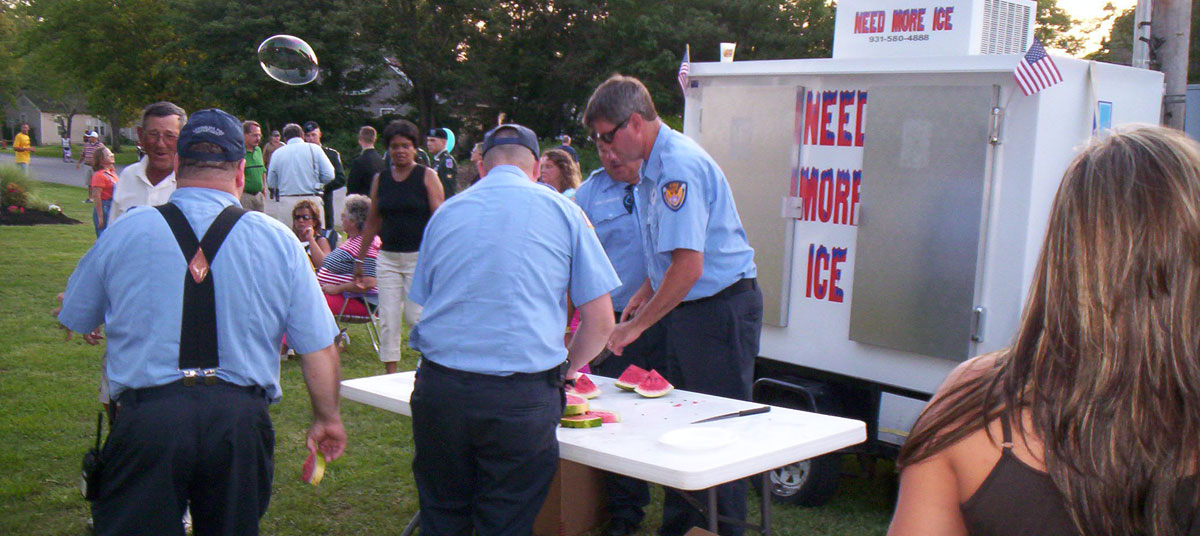 Firefighters server watermelon at a public event.